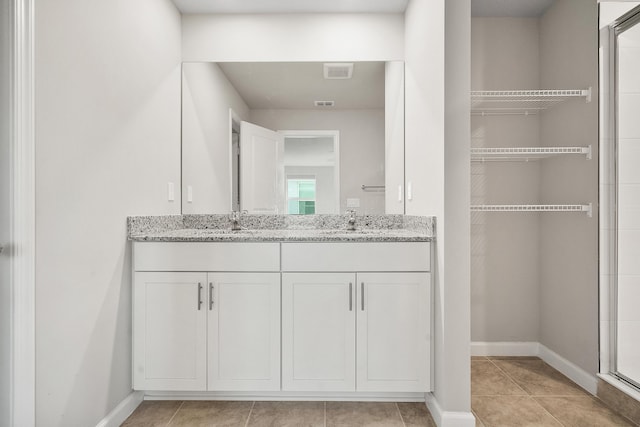 bathroom featuring tile patterned flooring, vanity, and a shower with door