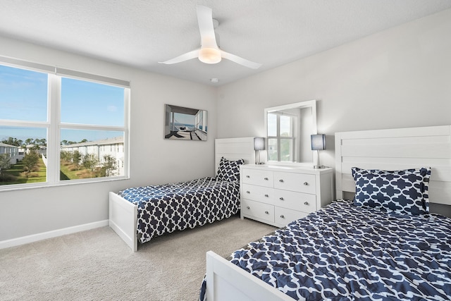 bedroom featuring ceiling fan, light colored carpet, and a textured ceiling