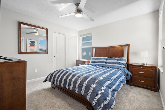 bedroom featuring light carpet, a closet, ceiling fan, and a textured ceiling