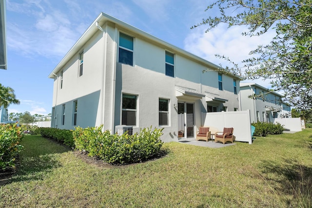 rear view of property with a patio and a lawn