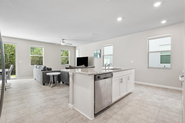 kitchen with light stone counters, stainless steel dishwasher, sink, a center island with sink, and white cabinetry