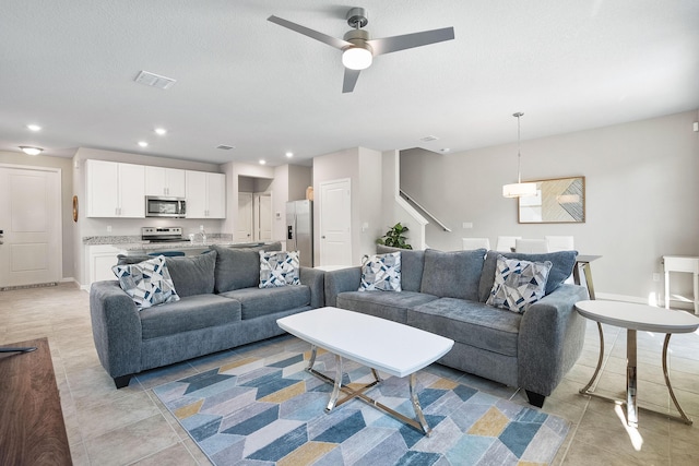 living room with light tile patterned floors, a textured ceiling, and ceiling fan