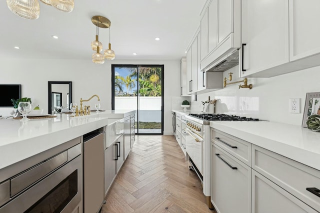 kitchen featuring white cabinetry, decorative light fixtures, light parquet flooring, custom range hood, and appliances with stainless steel finishes