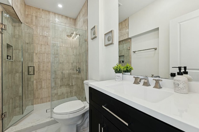 bathroom featuring vanity, a shower with shower door, and toilet