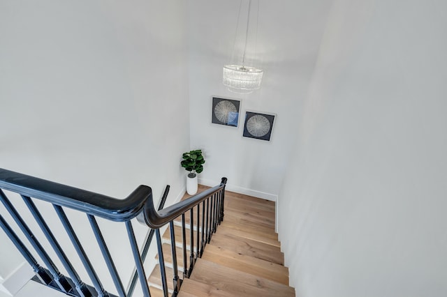 stairway with hardwood / wood-style floors and an inviting chandelier