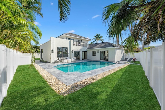 rear view of house with a fenced in pool, a patio area, a balcony, and a lawn