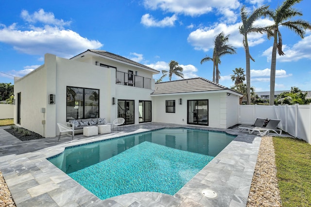 rear view of house featuring a patio, a balcony, an outdoor hangout area, and a fenced in pool