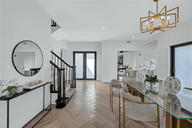 foyer featuring ceiling fan with notable chandelier, french doors, and light parquet flooring