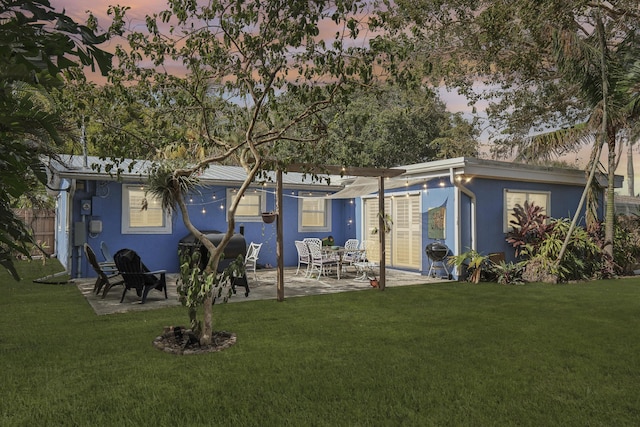 back house at dusk with a yard and a patio