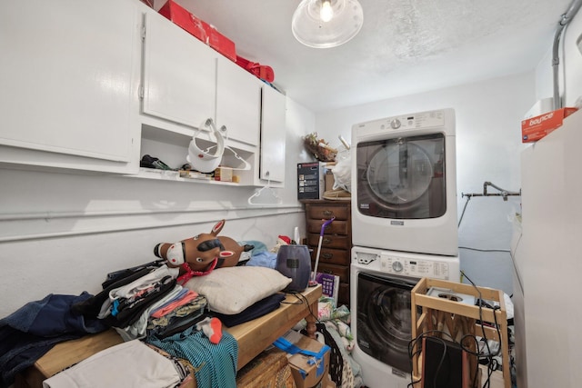 laundry area featuring stacked washer and dryer and cabinets