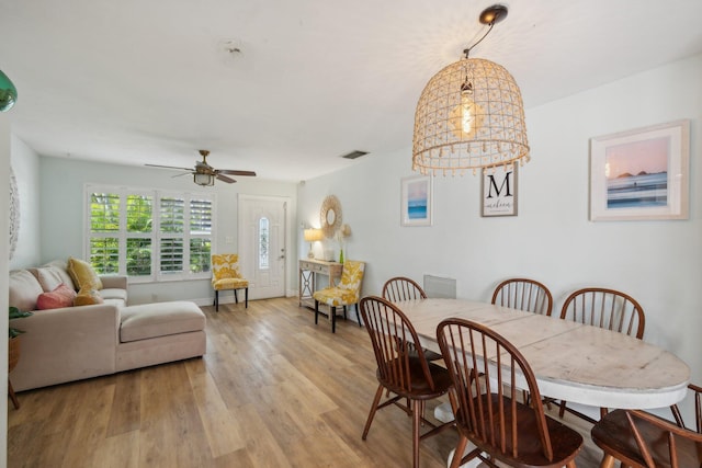 dining area with ceiling fan with notable chandelier and light hardwood / wood-style flooring