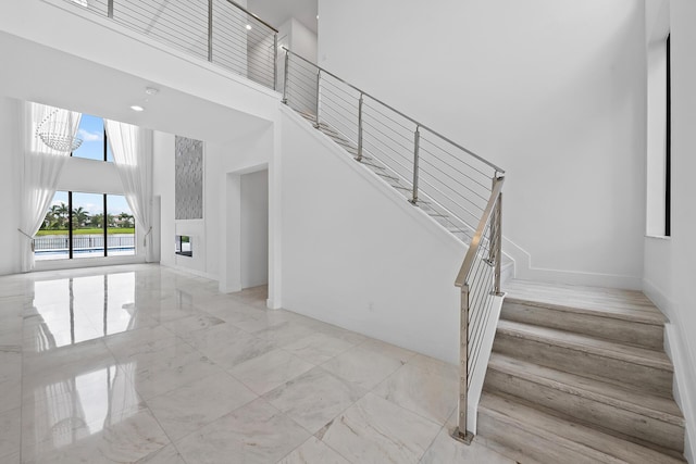 staircase with a chandelier and a towering ceiling