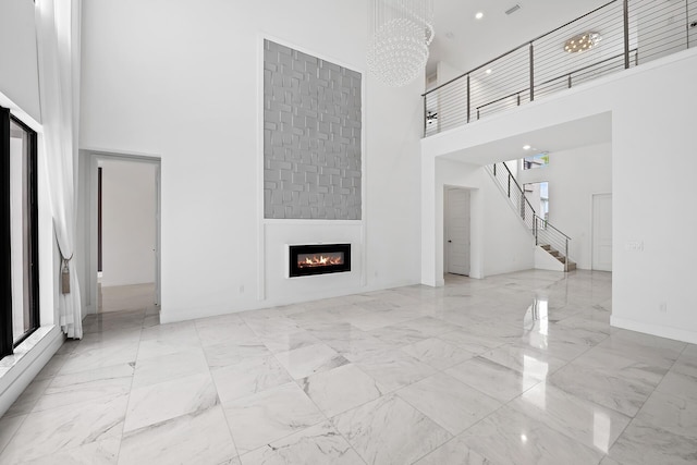 unfurnished living room featuring a chandelier and a towering ceiling