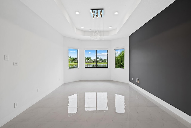 spare room featuring a chandelier and a tray ceiling