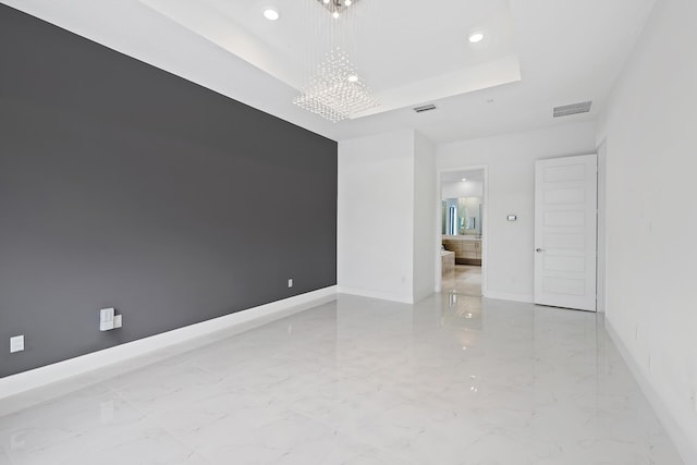 empty room featuring a tray ceiling and an inviting chandelier