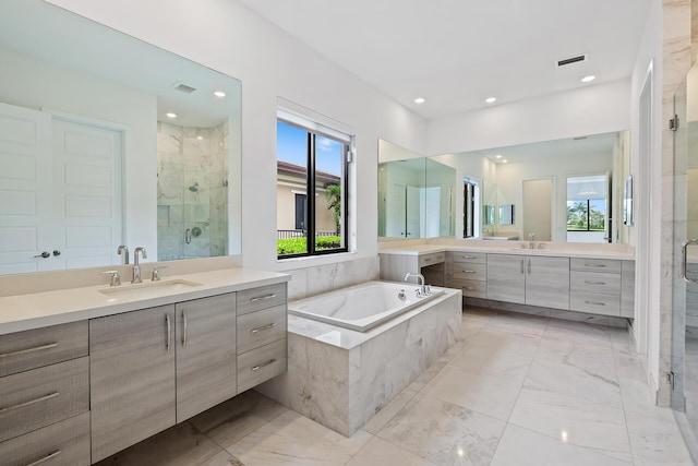 bathroom with plus walk in shower, vanity, and a healthy amount of sunlight