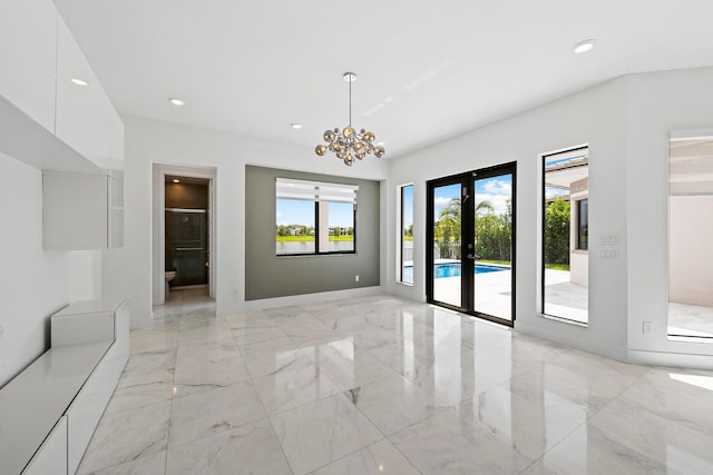 spare room with an inviting chandelier and french doors