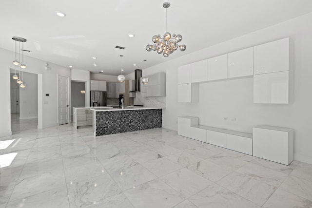 kitchen featuring an inviting chandelier, white cabinets, wall chimney range hood, stainless steel refrigerator with ice dispenser, and decorative light fixtures