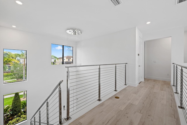 hallway with light hardwood / wood-style flooring and a notable chandelier