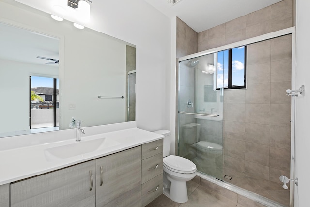 bathroom featuring tile patterned floors, vanity, toilet, and a shower with shower door