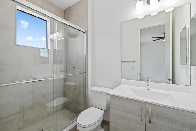 bathroom with ceiling fan, a shower with door, vanity, and toilet