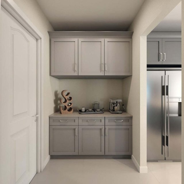 kitchen featuring stainless steel refrigerator, gray cabinets, and light tile patterned flooring