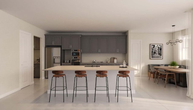 kitchen featuring light tile patterned floors, stainless steel appliances, a notable chandelier, and an island with sink