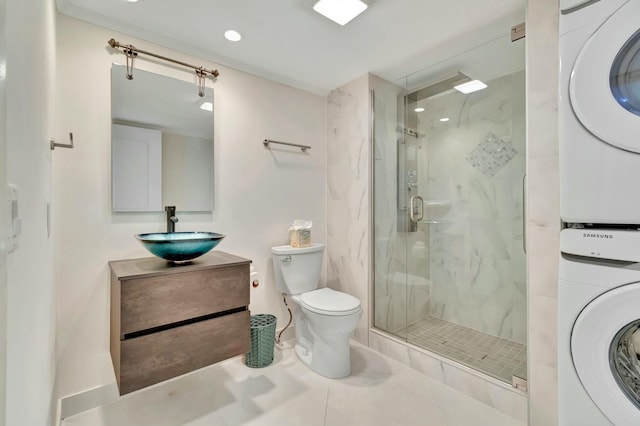 bathroom featuring vanity, walk in shower, stacked washer / drying machine, toilet, and tile patterned floors