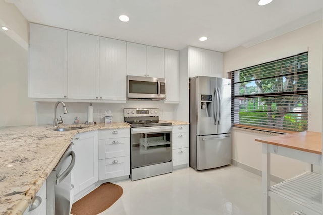 kitchen with white cabinets, light stone counters, sink, and appliances with stainless steel finishes