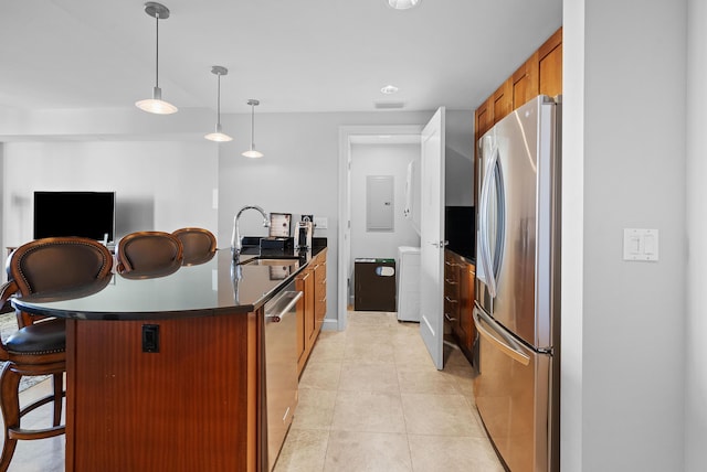 kitchen with a kitchen breakfast bar, sink, light tile patterned floors, decorative light fixtures, and stainless steel appliances