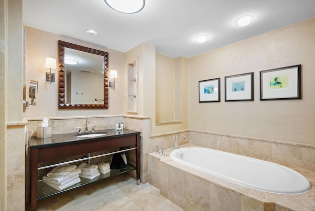 bathroom with tiled bath, tile patterned flooring, and vanity