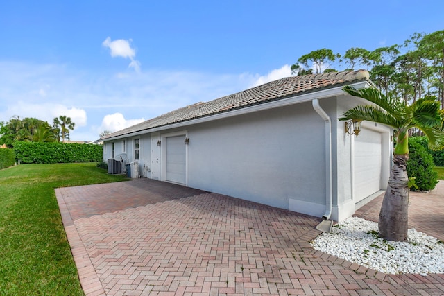 exterior space featuring central air condition unit, a yard, and a garage