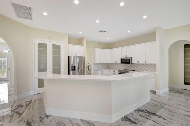 kitchen featuring sink, stainless steel appliances, a spacious island, decorative backsplash, and white cabinets