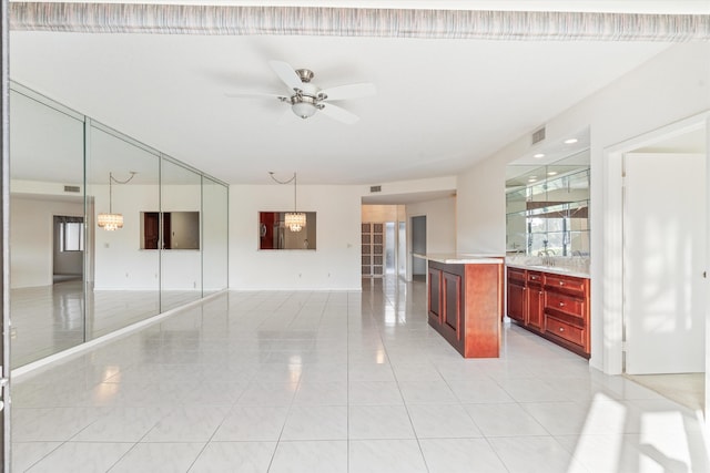 kitchen featuring light tile patterned floors, ceiling fan with notable chandelier, a center island, and hanging light fixtures