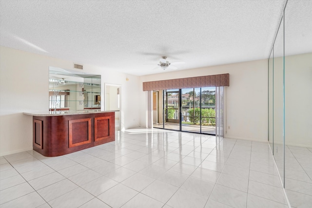 bar featuring ceiling fan, light tile patterned flooring, and a textured ceiling