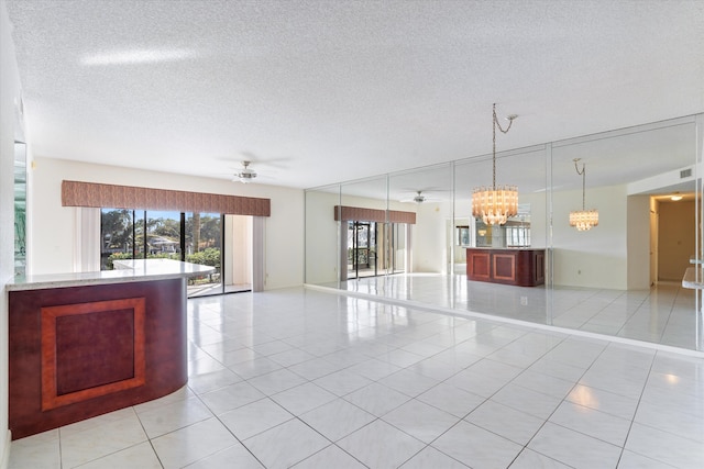 interior space featuring pendant lighting, ceiling fan with notable chandelier, a textured ceiling, and light tile patterned floors