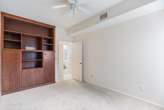 unfurnished bedroom with a textured ceiling, ceiling fan, and light carpet