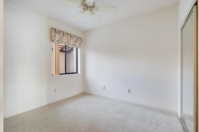 spare room featuring ceiling fan, light carpet, and a textured ceiling