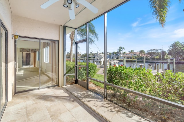 unfurnished sunroom with ceiling fan and a water view