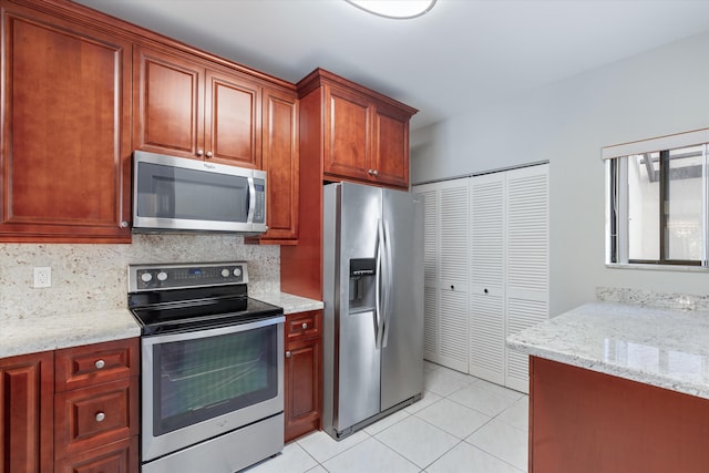 kitchen with decorative backsplash, light stone counters, light tile patterned floors, and appliances with stainless steel finishes