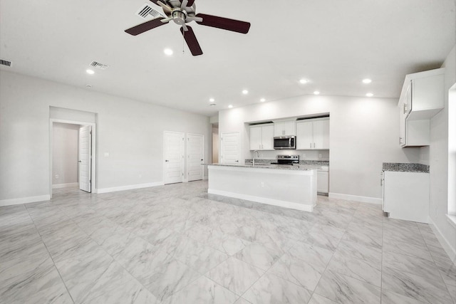 kitchen featuring appliances with stainless steel finishes, vaulted ceiling, a kitchen island with sink, sink, and white cabinets