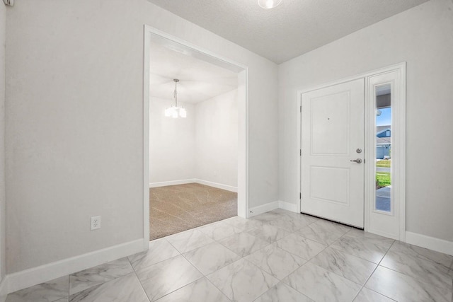 carpeted foyer with a notable chandelier and a textured ceiling