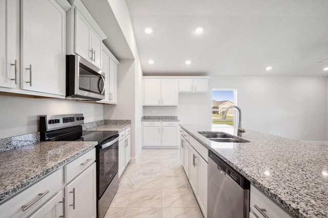 kitchen with appliances with stainless steel finishes, light stone counters, white cabinetry, and sink