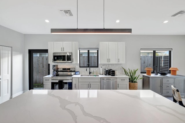 kitchen with decorative light fixtures, a center island, stainless steel appliances, and a wealth of natural light