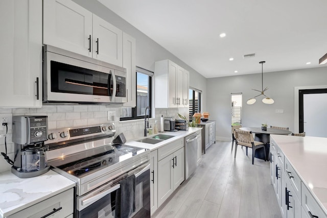 kitchen featuring a wealth of natural light, white cabinetry, pendant lighting, and stainless steel appliances