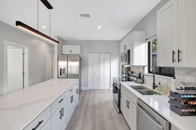 kitchen with white cabinets, stainless steel appliances, hanging light fixtures, and sink