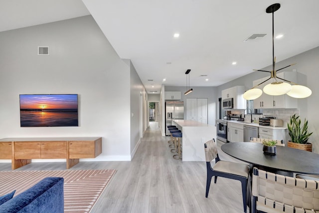 dining space featuring light wood-type flooring, vaulted ceiling, and sink