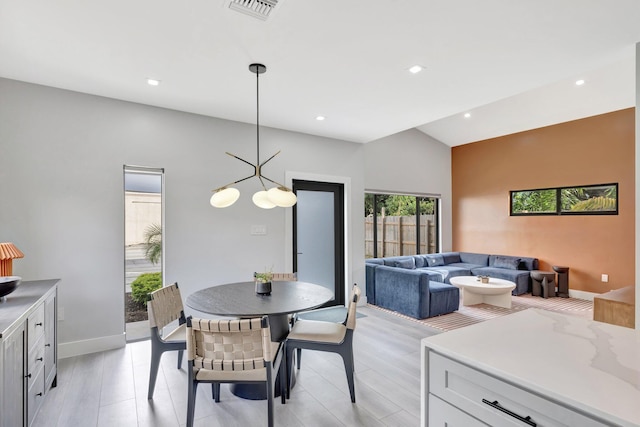 dining room with light hardwood / wood-style floors, lofted ceiling, and a notable chandelier