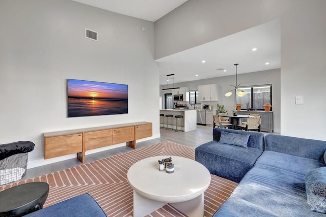 living room featuring light hardwood / wood-style flooring, a high ceiling, and an inviting chandelier