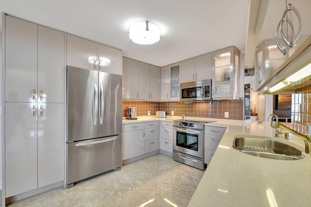 kitchen featuring gray cabinetry, appliances with stainless steel finishes, sink, and backsplash